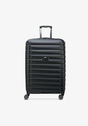Valigia nera rigida con design a riga, manico telescopico e quattro ruote girevoli. Presenta un logo rotondo sul davanti.
