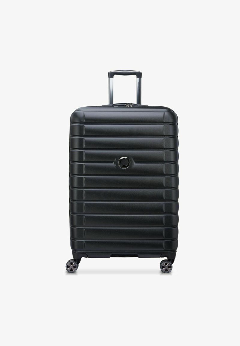 Valigia nera rigida con design a riga, manico telescopico e quattro ruote girevoli. Presenta un logo rotondo sul davanti.