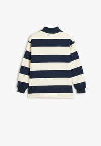 Camisa polo de manga larga a rayas en navy y crema, con un cuello alto y puños acanalados, que presenta un corte relajado y está confeccionada en suave algodón.