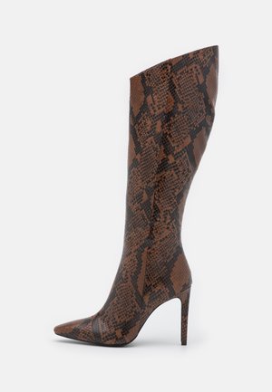 Høj stiletstøvle i brunt og sort slangeskindsprint med spids tå og slank høj hæl på hvid baggrund.