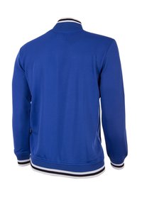 Blå jacka med en ribbad krage som har vita och svarta ränder, långa ärmar och en slät yta. Bakåtsidan har minimala sömdetaljer.