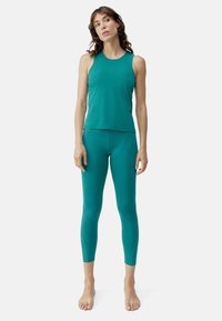Turkis atletisk tanktop og tights laget av elastisk materiale. Tightsene har teksturerte detaljer langs beina og en tettsittende design.