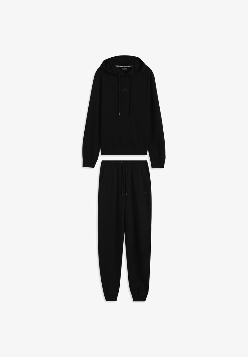Sudadera negra con capucha, bolsillo frontal y cordones, combinada con pantalones jogger negros con cintura elástica y bolsillos laterales.