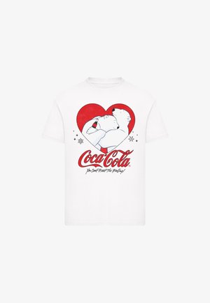 White cotton t-shirt featuring a red heart graphic with two polar bears and a Coca-Cola bottle, along with the brand's logo and slogan.