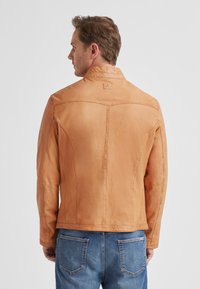 Herren-Lederjacke in Hellbraun mit tailliertem Schnitt, Schulternähten und glatter Textur. Mit hohem Kragen und Rückenteil-Design.