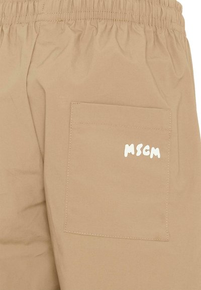 Short beige avec taille élastique et une poche arrière ornée d'un logo MSCM blanc sur le côté droit.