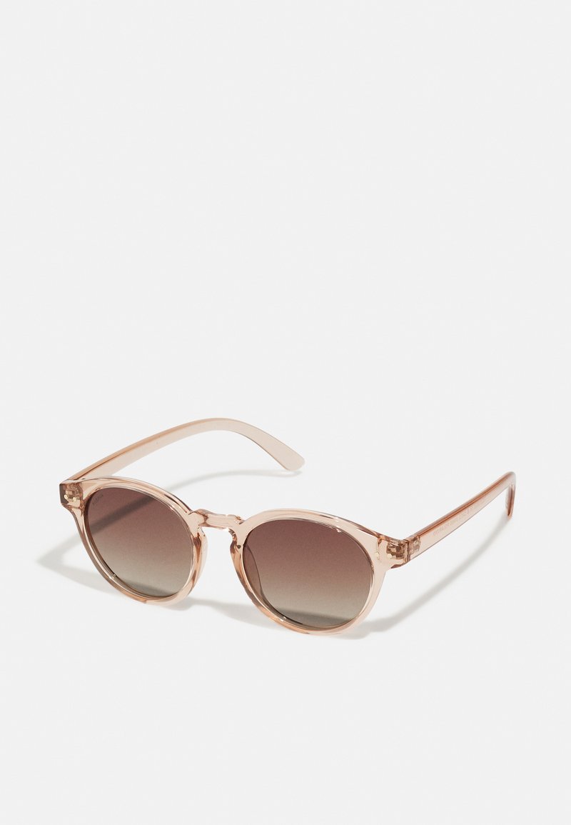 Round sunglasses with a translucent light pink frame and gradient brown lenses. Arms are sleek and slightly curved with subtle detailing.
