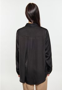Camicia nera in tessuto satinato, con maniche lunghe, polsini abbottonati, una piega sul retro e colletto, caratterizzata da una texture liscia e una vestibilità rilassata.