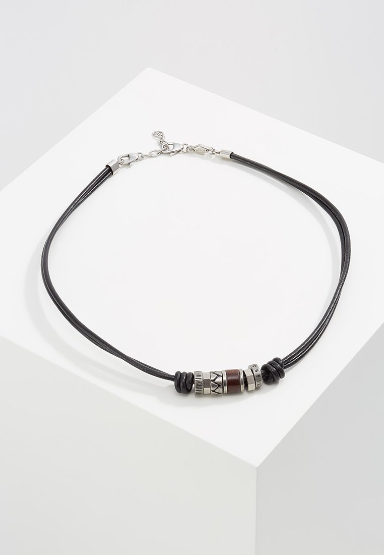 Schwarze Lederkette mit silberfarbenen Metallelementen, einer braunen Perle und gemusterten Metaldetails. Verstellbarer Verschluss für einen sicheren Sitz.