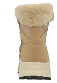 Beige winterlaars met een luxe crème bontvoering aan de bovenkant, glad synthetisch materiaal, robuuste, gestructureerde zool en contrasterende stiksels.