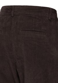 Pantalon en velours côtelé brun foncé montrant la ceinture arrière et deux poches passepoilées horizontales sans boutons ni rabats.