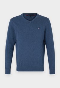 Blue v-neck sweater made of soft fabric, featuring long sleeves and a ribbed hem. Small logo accent on the chest.