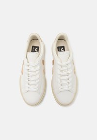 Hvite lær sneakers med beige detaljer, rund tå og flat gummisåle. Har seks snøringer og klassisk snøredesign.