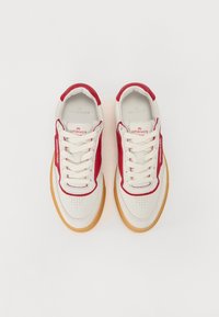 Baskets avec une tige en cuir blanc agrémentée d'accents rouges, embout texturé, lacets ronds et semelle en caoutchouc gomme. Marquage sur les côtés.