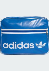 Geantă din vinil albastru cu accente albe și un logo Adidas mare alb. Dispune de o buzunar cu fermoar, cu un fermoar albastru în contrast.