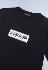 Fekete pamutszíj, fehér téglalap alakú logóval, rajta a "NAPAPIJRI" és "geographic" felirat fekete betűkkel. Ribbed kerek nyak.