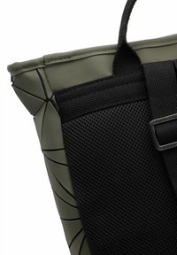 Bolsa de mano de goma verde con panel de malla negro, que presenta líneas de diseño angulares, costuras resistentes y un asa robusta para llevar.