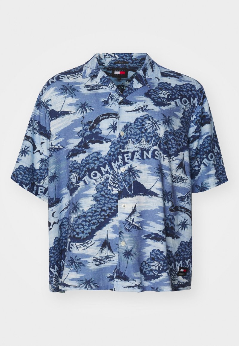 Camicia a maniche corte con bottoni in tessuto blu, caratterizzata da una stampa di scene tropicali con palme e velieri, con il marchio "Tommy Jeans" in bianco.