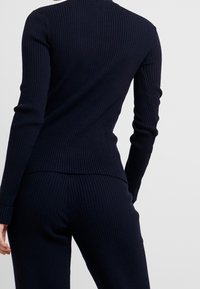 Marineblauw geribbelde lange mouw top, aangesloten ontwerp met een hoge halslijn en een textuurafwerking, gedragen met bijpassende geribbelde broek.
