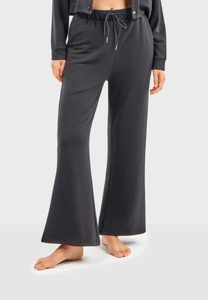 Dunkelgraue, ausgestellte Lounge-Hosen aus weichem Stoff, mit einem elastischen Bund und einer Kordel sowie sichtbaren Nähdetails.