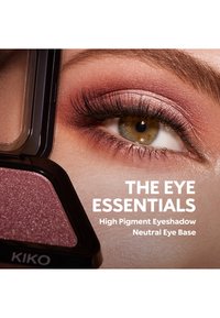 Close-up van een hazelnootkleurige oog met glinsterende roze en paarse oogschaduw naast een open oogschaduwdoosje met het label KIKO.