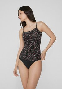 Černý tankini top s květinovým potiskem a tenkými nastavitelnými ramínky, zdobený na bocích nařasením, doplněný černými bikinovými kalhotkami.