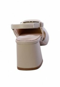 Sandal con tacco chunky di colore beige chiaro, con cinturino regolabile alla caviglia e parte superiore in morbida ecopelle. Suola piatta con una leggera curvatura.