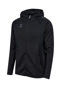 Zwarte capuchonjas gemaakt van zacht, lichtgewicht materiaal. Voorzien van een volledige ritssluiting, twee zijzakken en gestructureerde accenten aan de zijkanten.