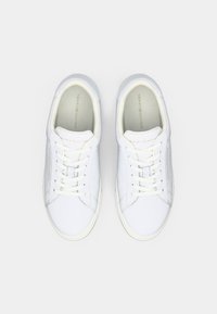 Bílé tenisky vyrobené z hladké kůže, s kulatou špičkou, tkaničkami a označením "TOMMY HILFIGER" na boku. Minimalistický design.