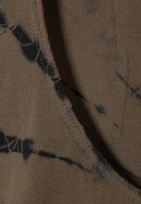Brauner Stoff mit einem Batikmuster und dunkleren Spritzern. Die Textur ist glatt, und der Stoff hat einen sauberen Rand mit einem leichten Glanz.