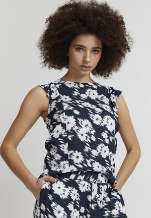 Blouse marine avec motif floral blanc, détails froncés sur les épaules et coupe décontractée. Fabriquée en tissu léger, idéale pour les journées chaudes.