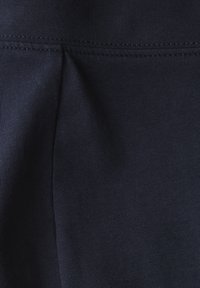 Marinblått tyg med en slät textur, med en subtil lyster; inkluderar sydda sömmar för struktur och hållbarhet.