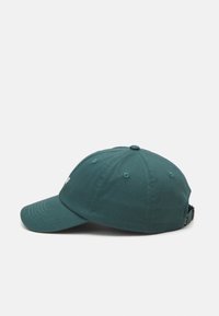 Tölgy színű pamut baseball sapka ívelt árnyékkal, varrott részletekkel, szellőzőlyukakkal és hátul állítható pánttal. Fehér logó elöl.