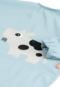 Blauwe waterdichte schort met een lichtgrijze koe ontwerpen met zwarte vlekken en een groene accenten. Inclusief elastische mouwen voor een veilige pasvorm.