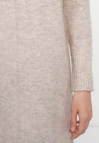 Maglione lavorato a maglia di un delicato rosa, con polsini a coste e una consistenza liscia, caratterizzato da un sottile motivo melangiato e una silhouette dritta.