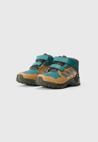 Botas de caminhada com um esquema de cores turquesa e castanho, feitas de materiais em malha e sintéticos, com tiras ajustáveis e solas texturizadas.