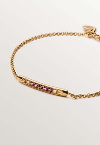 Pulsera de oro que presenta una barra curvada con cinco piedras preciosas moradas y claras, unidas por una delicada cadena, mostrando superficies lisas y pulidas.