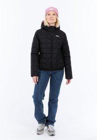 Giacca a vento nera trapuntata con cappuccio, con zip frontale e due tasche laterali. Berretto rosa in lana. Jeans in denim blu e sneakers grigie.