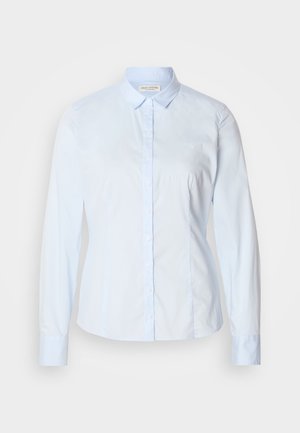 Camisa azul clara com botões, mangas compridas, colarinho clássico e um logo subtil bordado no peito. Tecido liso e nítido.