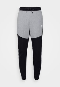 Nike-joggingbyxor med en grå övre del och svart nedre del, tillverkade av mjukt tyg med justerbar midja och logotypdetalj.