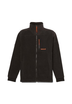 Chaqueta de forro polar negra con cuello alto, cremallera frontal y bolsillo en el pecho. Cuenta con un tirador de cremallera naranja y una pequeña marca en el bolsillo.