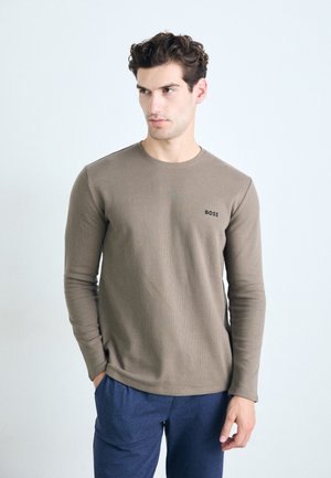 Braunes langärmliges T-Shirt aus strukturiertem Stoff, mit Rundhalsausschnitt und dezentem 'BOSS'-Logo auf der Brust, kombiniert mit blauen Hosen.