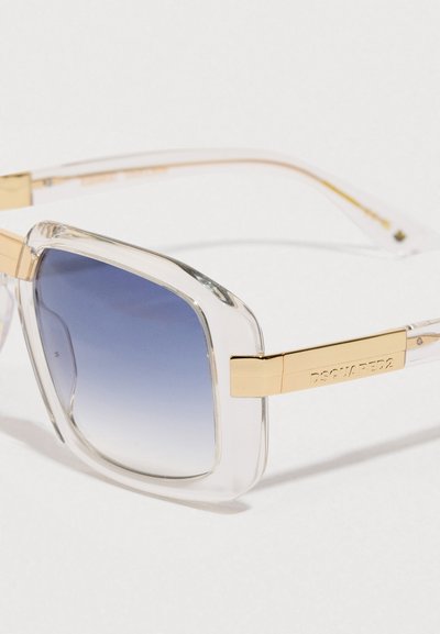 Occhiali da sole quadrati con montatura trasparente e lenti blu sfumate, dotati di stanghette in metallo dorato incise con il nome del marchio.