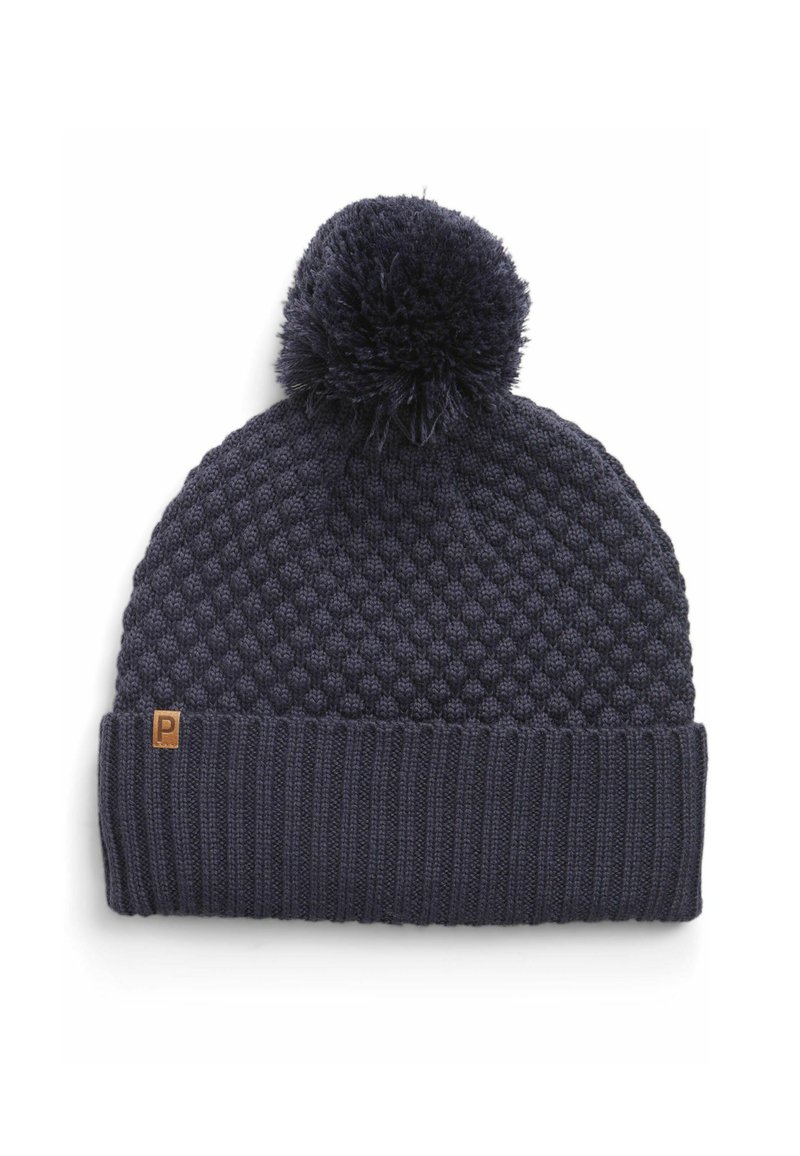Navy knitted beanie with a textured body, ribbed cuff, and a fluffy pom-pom on top. Accented with a small brown label.