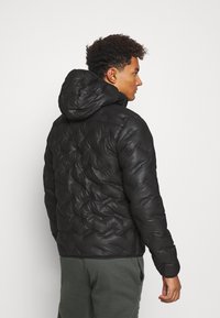 Schwarze Daunenjacke mit Kapuze, die ein gestepptes Design und glänzende Textur aufweist. Die Jacke ist mit elastischen Bündchen und einem Taillenzug vollendet.