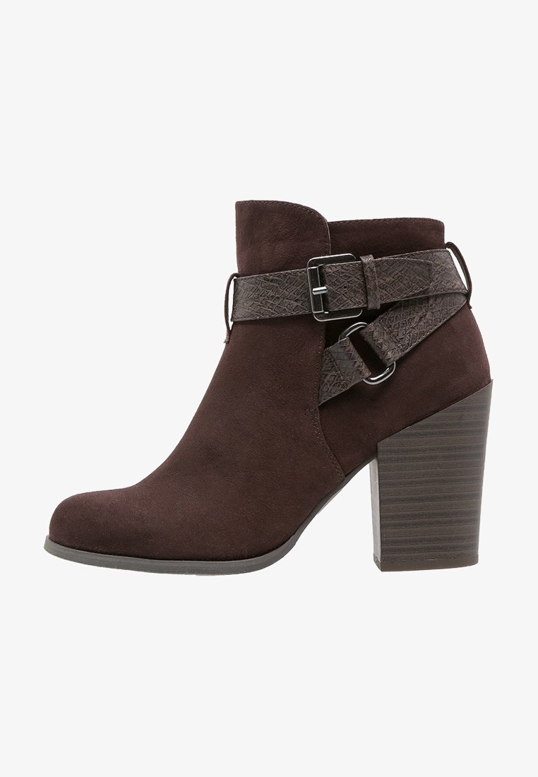 Brown suede ankle boot with a textured leather strap and buckle detail. Rounded toe and a stacked, ribbed heel.