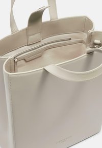 Jasnobeżowa torba na ramię z gładkiej skóry. Wnętrze posiada kieszeń zamykaną na zamek błyskawiczny oraz staranne szwy. Solidne uchwyty ułatwiają noszenie.