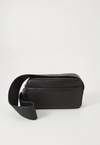 Black leather crossbody bag with a smooth texture, rectangular shape, zippered closure, and an adjustable shoulder strap. Minimalist design.