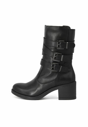 Stivale alla caviglia in pelle nera con tre cinturini regolabili con fibbie, punta arrotondata e tacco chunky di 7 cm. Texture liscia e dettagli di cucitura minimali.
