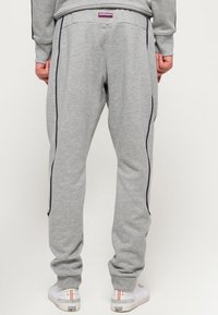 Grijze sweatpants van een katoenmix, met zijpiping in marineblauw en een elastische tailleband. De pasvorm is ontspannen met taps toelopende benen.